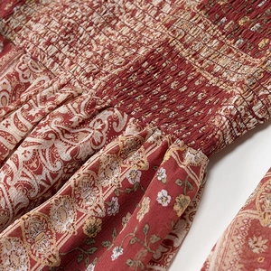 Detail of red paisley dress showing intricate smocking and textured cotton linen fabric