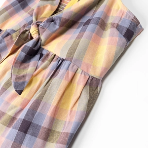 Detail of plaid dress showing a decorative bow tie and gathered texture on cotton fabric
