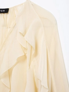 Close-up of cream chiffon blouse featuring layered ruffle details and soft fabric texture