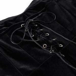 Détail de robe en velours noir avec lacets, oeillets métalliques et fermeture éclair latérale