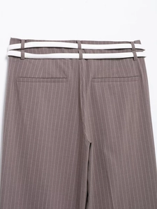 Dettaglio di pantaloni gessati con tasche posteriori e doppie cinture sottili bianche