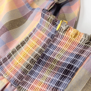 Macro shot of colorful plaid fabric with detailed smocking and yellow hidden zipper