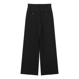 Detail view of high-waist black wide-leg pants featuring buttoned back welt pockets