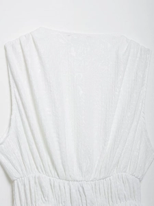 Detail of white dress fabric showing textured jacquard patterns and elastic waist design
