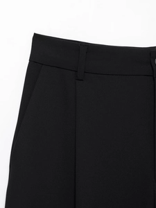 Detail of waist structure on black wide-leg trousers featuring belt loops and pocket seams