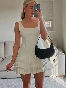 Detail view of white sleeveless mini dress with pleated hem and square neckline