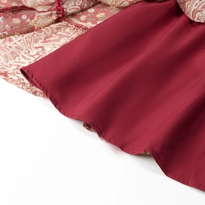 Detailed macro view of bohemian dress paisley print fabric with wine red lining and stitching