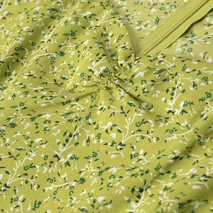 Detail view of green floral dress with neckline zipper and ruffled chiffon fabric texture