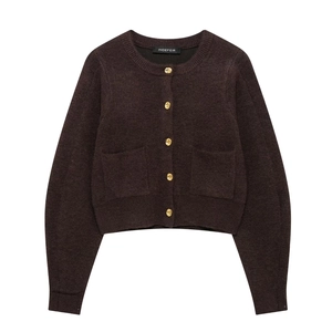 Close-up of dark brown knit cardigan featuring ornate gold embossed buttons and pocket details