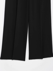 Detailed view of black wide-leg trousers featuring elegant vertical pleats and draped fabric