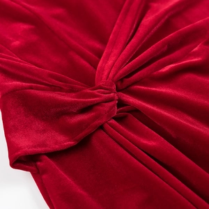 Détail macro d'une robe en velours rouge avec un design sophistiqué de nœud tordu