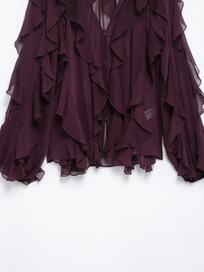 Detail of burgundy chiffon blouse showing layered ruffles and delicate round buttons
