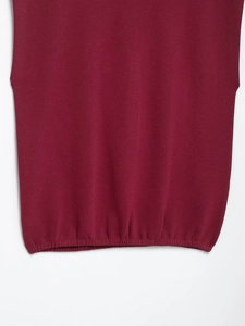 Detail shot of burgundy knit vest hem featuring fine flat stitch texture and ribbed finish