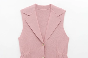 Détail du gilet en maille rose poudré avec col à revers et boutons métalliques dorés