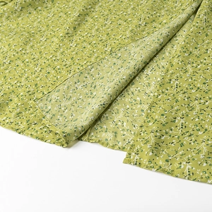 Close-up of light green floral print fabric with rolled hem stitching on the summer dress