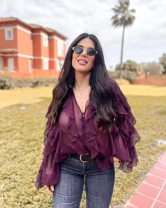 Close-up of elegant ruffled layers and sheer chiffon texture on a deep purple V-neck blouse