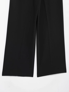 Detail view of black wide-leg trousers featuring sharp center creases and a straight cut