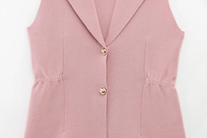 Détail du gilet en tricot rose avec boutons métalliques dorés et plis à la taille