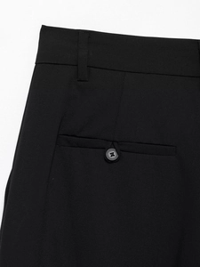 Detailed close-up of a black wide-leg trouser featuring a buttoned back welt pocket and belt loops