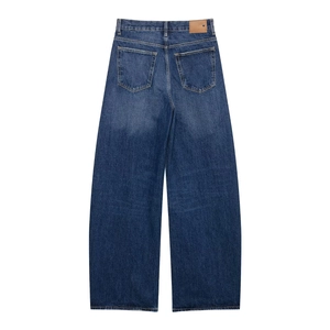 Détail d'un jean bleu foncé avec poches arrière et patch logo en cuir à la taille