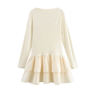 Detail of cream long sleeve dress featuring tiered ruffled hemline and round neckline