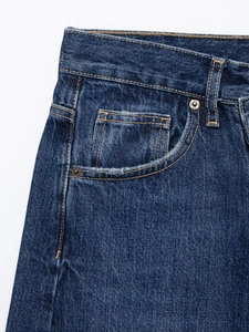 Détail du tissu denim bleu foncé avec tissage sergé blanc et rivets métalliques polis