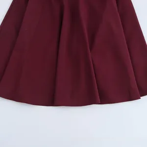 Gros plan sur l'ourlet plissé bordeaux montrant la texture du tissu et les coutures