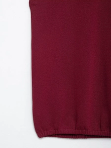 Detailed macro view of the burgundy knit fabric showing smooth stitch and ribbed hem texture