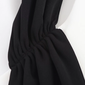 Détail du plissage et de la texture du tissu noir sur une robe courte minimaliste