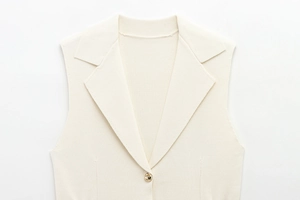 Détail du gilet en tricot crème avec revers à encoche et fermeture par bouton doré chic