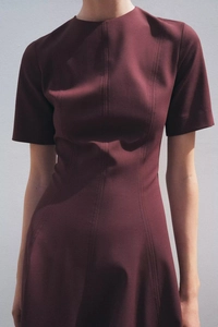 Détail de la robe bordeaux avec coutures verticales et taille cintrée au design plissé