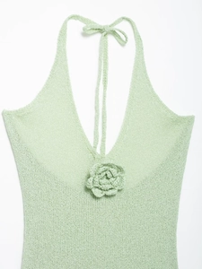 Detailed macro view of mint green crochet halter top with a 3D floral accent and knit texture