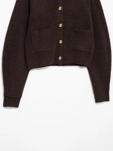 Macro shot of heavy coffee knit cardigan with detailed gold embossed buttons and pockets