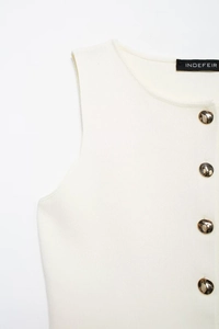 Vue détaillée du gilet en tricot crème avec boutons dorés et texture côtelée délicate