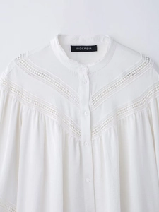 Detail of white long sleeve shirt showing delicate V-shaped lace embroidery and ruffles