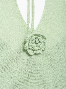 Detailed macro view of the mint green knit V-neckline with a 3D crochet flower accent