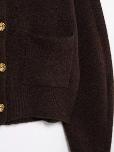 Detail of dark brown knit cardigan featuring golden buttons and soft wool texture