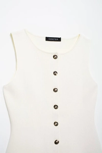 Détail de ce gilet en maille crème avec boutons à motif marbré et texture à fines côtes