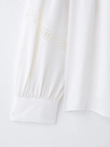 Detail of white long sleeve shirt showing delicate lace panels and pleated cuffs