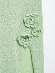 Detail of light green knit fabric featuring three handmade 3D crochet flowers on the slit