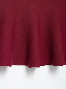 Detail of the wine red knit dress with ribbed texture and wavy hemline design