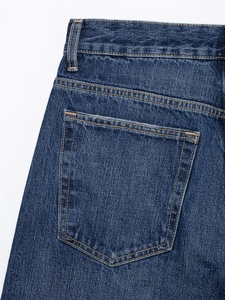 Gros plan détaillé d'un jean bleu foncé montrant les poches arrière et les surpiqûres