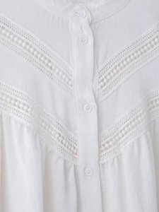Detailed close-up of white blouse featuring V-shaped lace crochet and elegant button closure