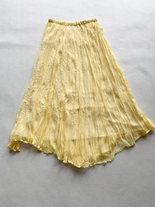 Detailed view of elastic waistband and pleated texture on a yellow maxi skirt