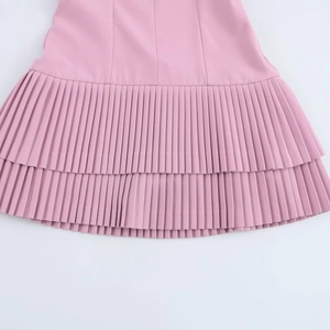 Close-up of pink layered dress featuring fine accordion pleats and textured fabric