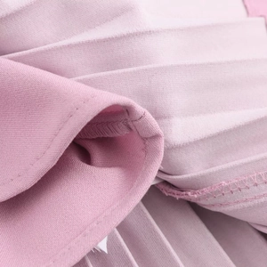Macro shot of pink pleated dress fabric showing precise pleats and detailed hem stitching