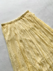 Detailed view of elastic waistband and pleated texture on the light yellow skirt
