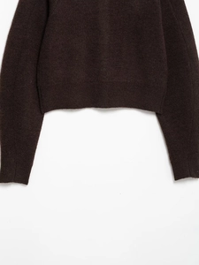 Detail of dark brown knitwear showing ribbed hem, cuffs, and soft wool texture