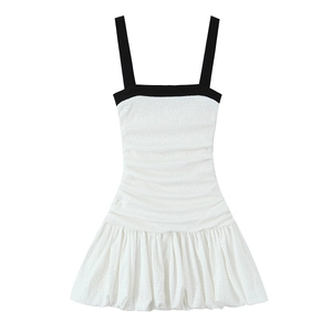 Detail of smocked texture and black contrast straps on the white mini dress