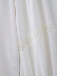 Detailed macro view of white cotton fabric texture with geometric lace trim detail